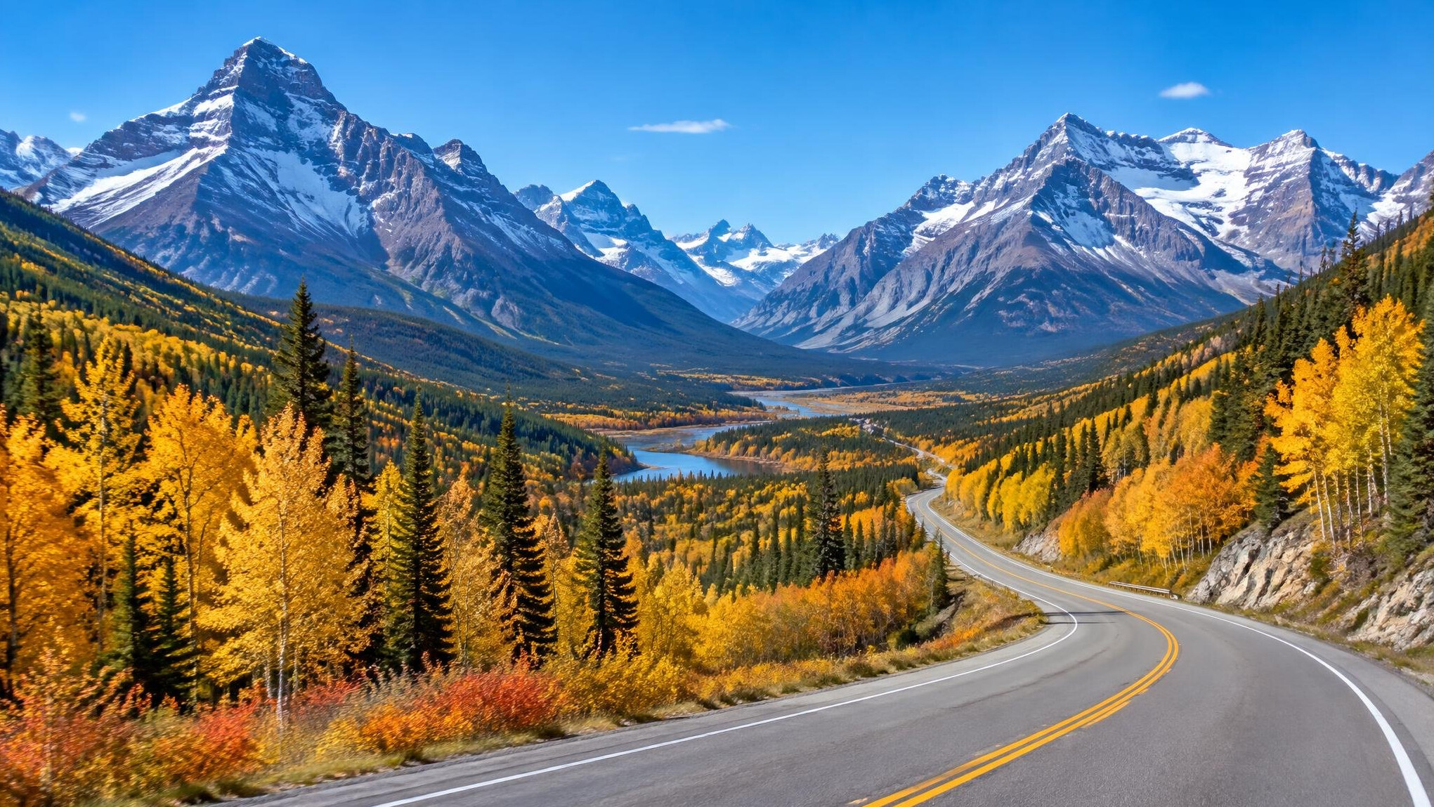 Wide view of the Canadian Rockies with a winding highway in autumn